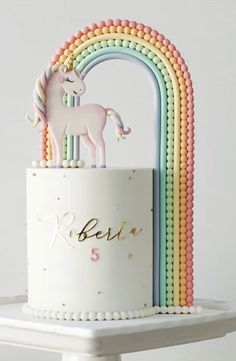 a white cake with a rainbow and a unicorn on top that says berea 5