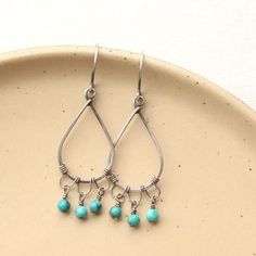 Forged silver teardrops have been uniquely wrapped with wire to create chandelier style earrings.  Little drops of deep turquoise dangle from the hand formed loops.  Delicate but not shy.  Handmade shepherd hook earwires.  Measure 2".  Sterling silver, which has been oxidized and hand polished for an antique finish.About Turquoise:  The name turquoise means "Turkish stone" because the trade route that brought it to Europe came via Turkey. Turquoise is a non-translucent stone of which the most va Teardrop Chandelier, Oxidized Silver Earrings, Deep Turquoise, Turquoise Earrings Dangle, Chandelier Style, Deep Teal, Oxidized Silver, Style Earrings, Antique Finish