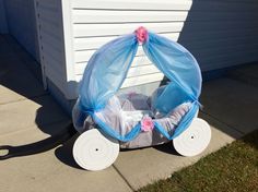 a baby carriage made out of plastic bags on the side of a house with blue netting and pink flowers