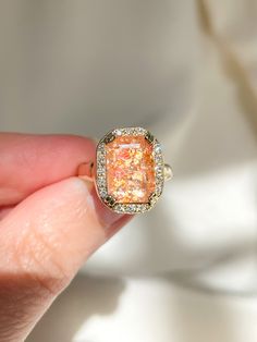 One of a kind (11x8mm) confetti Sunstone Ring hugged in 14k yellow gold and a halo of Diamonds, filled to the brim with iridescent rainbows and flecks of light, illuminated from within, this light-body is ready to embrace you with the warmth of the sun. 💌Please enter desired ring size in notes. **Currently a size 3.5, can be sized between a 3 - 6.5.** Sunstone embodies the sunlit personality, tapping into the archetypal masculine energy representing power, creative force, inspiration, motivatio Sun Stone Ring, Gold Emerald Cut Gemstone Halo Ring, Gold Opal Ring With Halo Design - Gift, Gold Emerald Cut Halo Jewelry, Emerald Cut Gold Halo Jewelry, Gold Opal Diamond Halo Ring, Gold Opal Halo Ring For Anniversary, Gold Opal Ring With Halo For Anniversary, Dazzling Gold Halo Ring