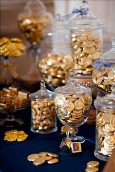 a table topped with lots of glass jars filled with gold coins