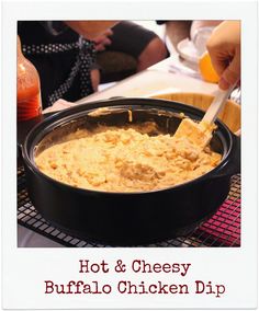 people are sitting at a table with food in bowls and one person is using a spoon to dip something into the bowl