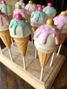 some ice cream cones with sprinkles and toppings on them sitting on a wooden tray