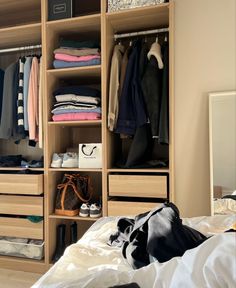 an organized closet with clothes, shoes and handbags on the bed in front of it