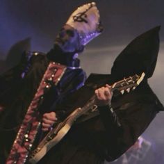 a man in costume holding a guitar on stage