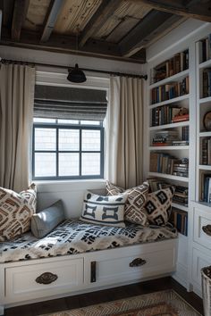 a window seat in the corner of a room with bookshelves and pillows on it