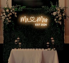 the table is set up with white linen and greenery for an elegant wedding reception