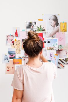 a woman standing in front of a wall with pictures on it's back side