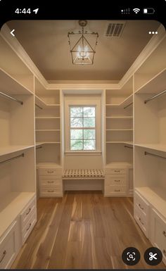 an image of a walk in closet with white shelves and drawers on one side, light wood floors