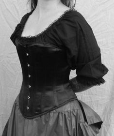 "Show your darker side in our c. 1860 Julia corset made in your size in shiny black satin. This 19th century hourglass shape distills into one corset the great range of the period's varying silhouettes. Lightly boned, it smoothes the line of the body from bust to hip. It is cut in the shorter French style of the period from shaped pieces. The satin coutil adds to the delicate and demure feeling of this simple silhouette. For the convenience of donning the corset by yourself we have included a ce Gothic Satin Corset With Boned Bodice, Gothic Black Corset With Medium Bust Support, Black Satin Underbust Corset, Gothic Black Boned Bodice, Black Satin Gothic Corset, Victorian Corset, Black Goth, Hourglass Shape, Front Open