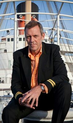 a man in a suit and tie sitting on a bench next to a large ship