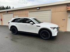 a white suv parked in front of a building with two garage doors on each side