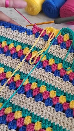 a crocheted blanket with yarn and knitting needles