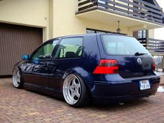 a blue vw golf wagon parked in front of a house with its door open