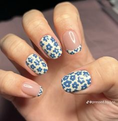 a woman's hand with blue and white flowers on it, holding up her nails