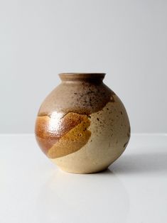 a brown and white vase sitting on top of a table