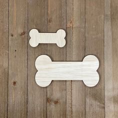 two wooden dog bone magnets on a wood floor