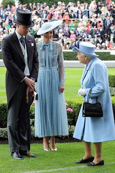 the queen and prince are talking to each other on the grass in front of an audience