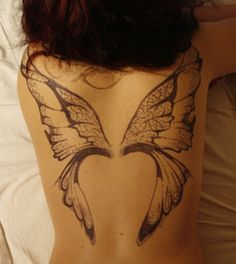 the back of a woman's body with a butterfly tattoo on her lower back