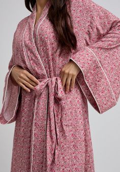 The charming Corina robe is cut from our inimitable cotton and adorned with an interesting pink Ditsy floral print. This oversized kimono-inspired robe boasts fluted sleeves and a detachable belt, creating a flattering silhouette. Contrast piping on the cuff and neck, complete this effortlessly feminine piece.  Cool machine wash only. Wash inside out and with similar colours 100% Cotton Sourced India  Cool machine wash only. Wash inside out and with similar colours