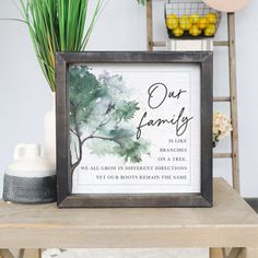 a framed sign with the words our family on it next to a potted plant