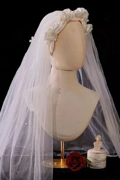 a mannequin wearing a wedding veil with flowers on the head and a rose