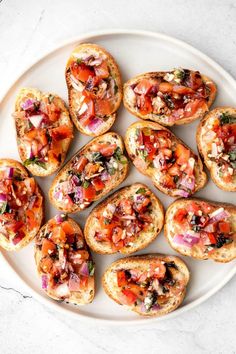 a white plate topped with mini breads covered in toppings on top of a table