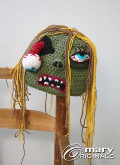 a crocheted monster head hanging from a wooden ladder