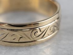 This handsome vintage band is easy and comfortable to wear! Beautifully stylized scrolling designs waft their way across the top of the band and are complemented by the smooth polish of the background. Metal: 14K Yellow Gold Width of Band: 5.8 mm Height off Finger: 1.3 mm Ring Size: 8.50 Marks: "12 14LK" Stamped on the inside band Elegant Engraved Adjustable Band, Classic Gold Engraved Bands, Gold Thick Decorative Band, Classic Engraved Gold Bands, Engraved Yellow Gold Bands For Formal Occasions, Classic Yellow Gold Band With Intricate Design, Formal Gold Engraved Bands, Formal Engraved Gold Bands, Engraved Thick Band Elegant