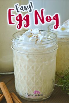 two mason jars filled with egg nog on top of a table next to cinnamon sticks