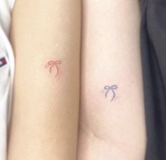 two people with matching tattoos on their arms, one is holding the other's arm