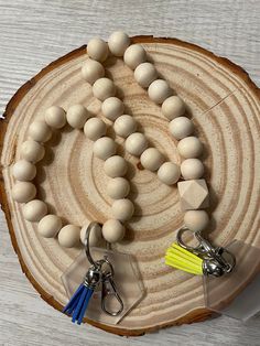 a wooden bead necklace with two tassels on it and a plastic keychain