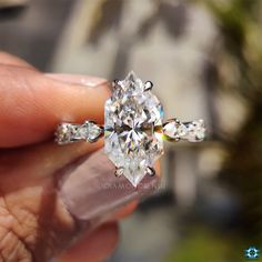 a person holding a diamond ring in their hand, with the center stone being surrounded by smaller diamonds