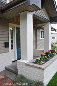 the front entrance to a house with flowers growing out of the planters on the side