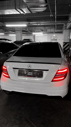 two cars parked in a parking garage with their lights on and the back door open