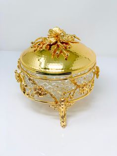 an ornately decorated box with gold trimmings and flowers on the lid is shown