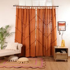 a living room with orange curtains and rugs