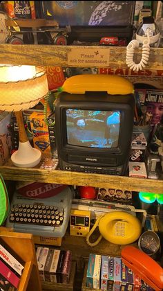 an old tv sitting on top of a wooden shelf next to a lamp and other items