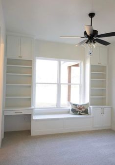 an empty room with a ceiling fan and white bookcases