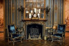 a living room with two chairs and a clock on top of the fireplace mantel