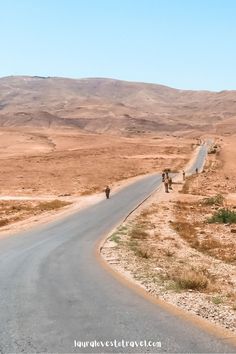 three people are walking down the road in the desert