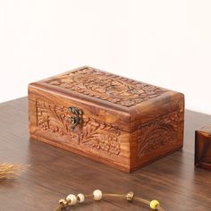 a wooden box sitting on top of a table next to two beads and a pen