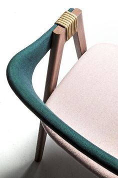 a chair with a wooden frame and green fabric on the back, in front of a white background