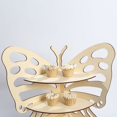 three tiered cake stand with cupcakes on it and a butterfly shaped top