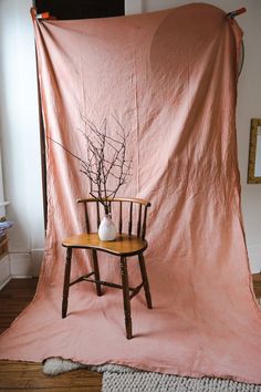 a chair with a vase sitting on top of it in front of a pink blanket