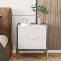 a white and gold nightstand next to a bed