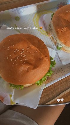 two hamburgers sitting on top of paper wrappers with words written in the middle