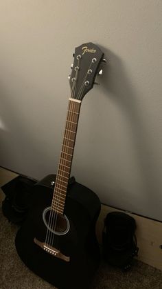 a black acoustic guitar sitting on top of a wooden floor