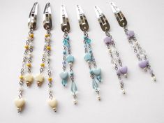 several different colored beads and chains attached to metal clips on a white surface with silver clasps