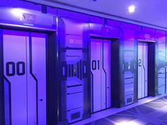 a room with purple and black doors in the center is lit up by bright lights